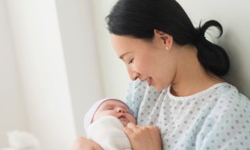 A mother holding her newborn baby in her hospital bed