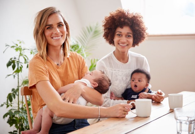 Stock photo of two women smiling at the camera with their babies (two)