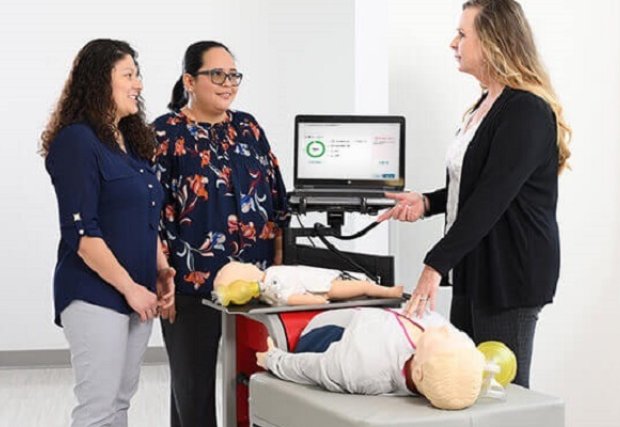 An instructor teaching two students CPR