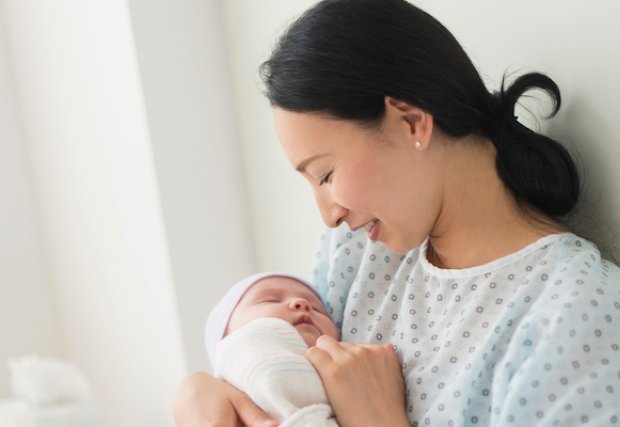 A mother holding her newborn baby in her hospital bed