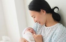 A mother holding her newborn baby in her hospital bed